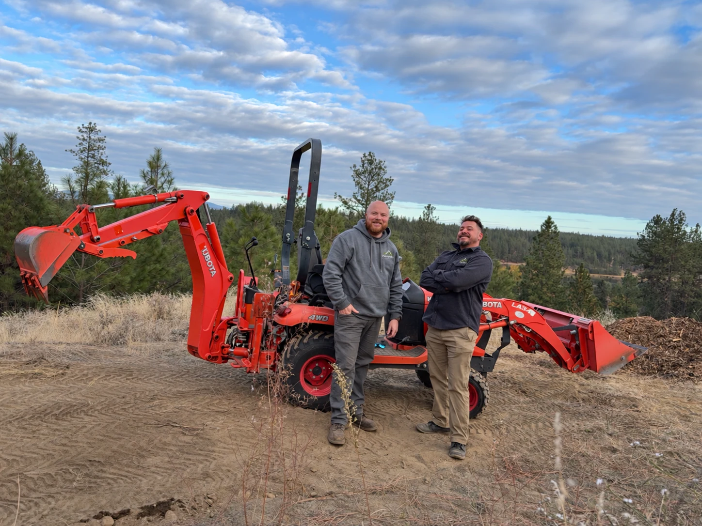 Chris and Iaian of Two Vets Siteworks standing beside their tractor