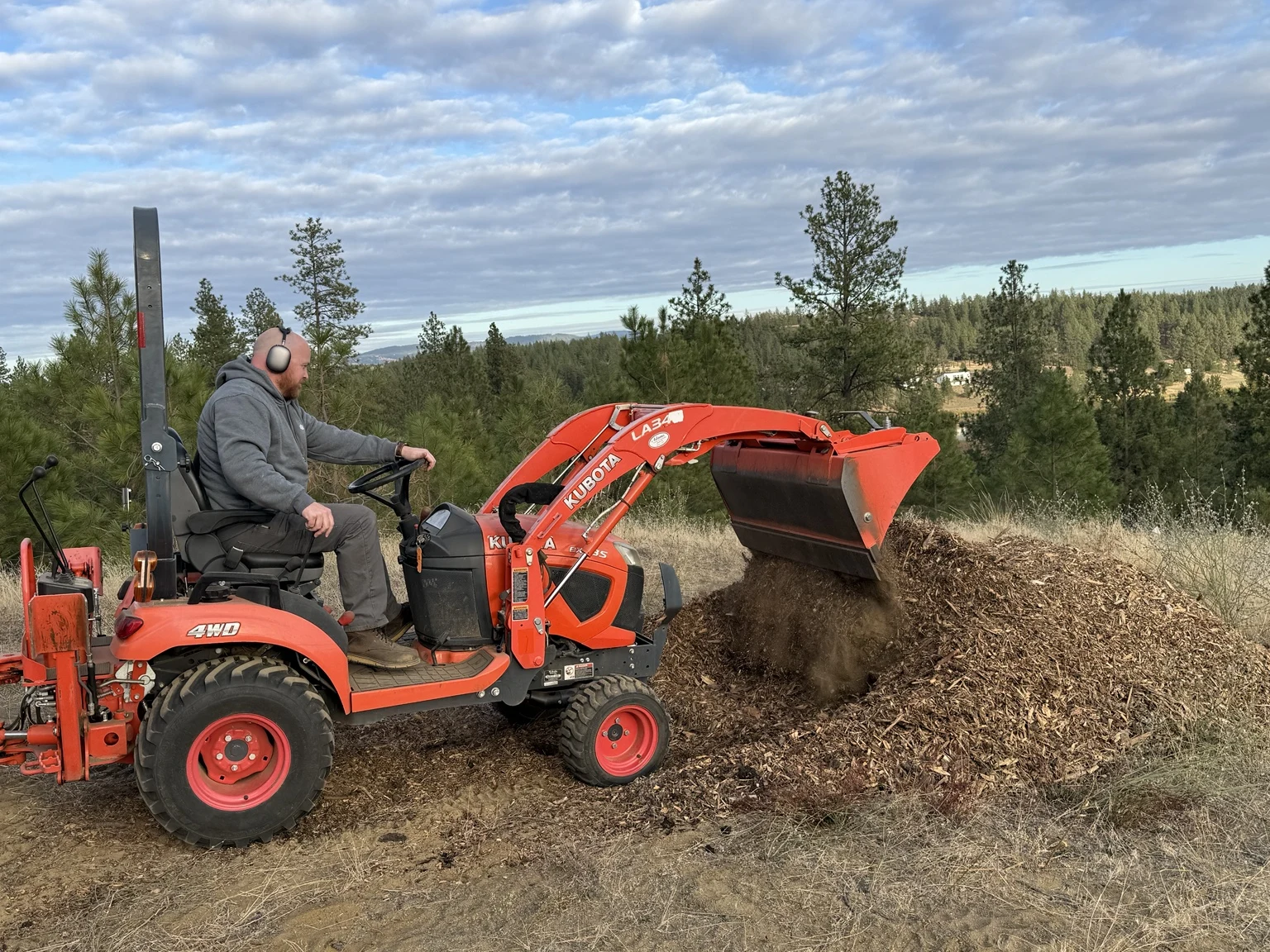 Tractor loader placing wood chips onto a material pile